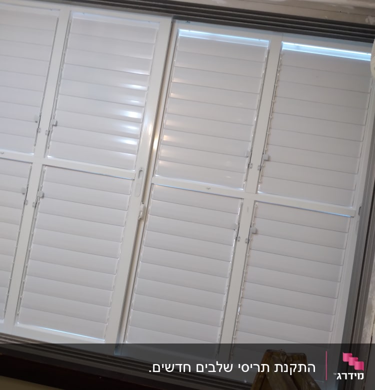 תריסים לבנים סגורים עם מסגרת מתכת